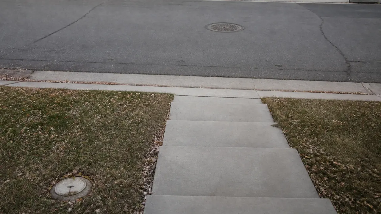 Residential sidewalk, curb, and street manhole in a Denver neighborhood